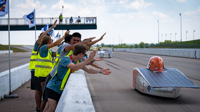 Solar Car on a track passing cheering fans