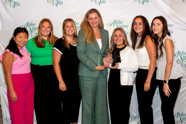 Seven women pose together for photo with award