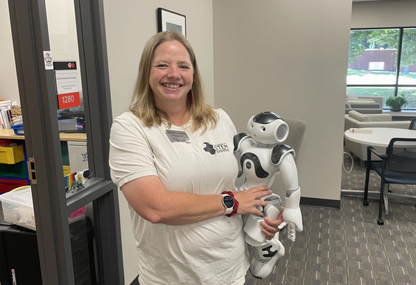 Emily Wonnacott-Stanley standing and holding a robot near her hip