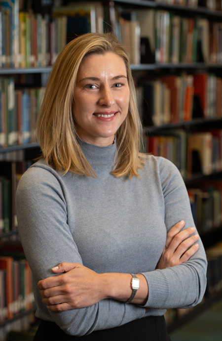 Portrait of Marlee Graser standing in front of stack of books