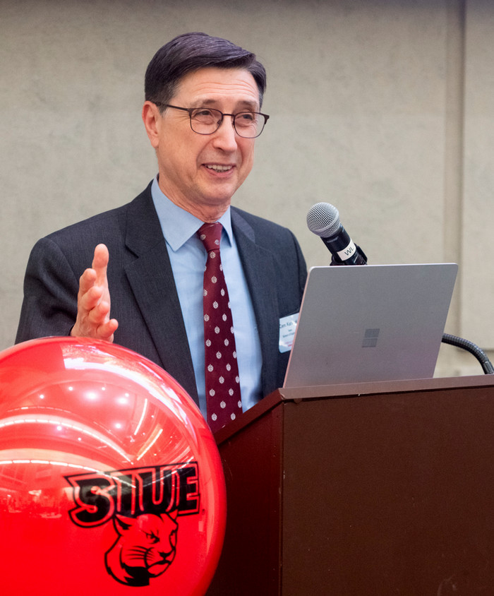 Dean Karacal speaking at a podium inside the atrium of the engineering building