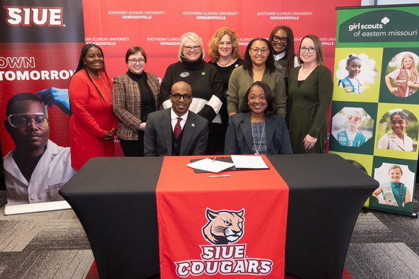 Girl Scouts and SIUE staff pose behind table signing of MOU