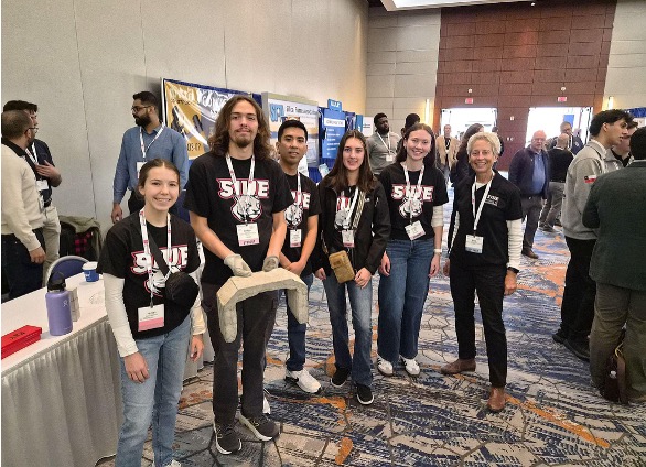 Group of students and professor at convention wearing team tshirts