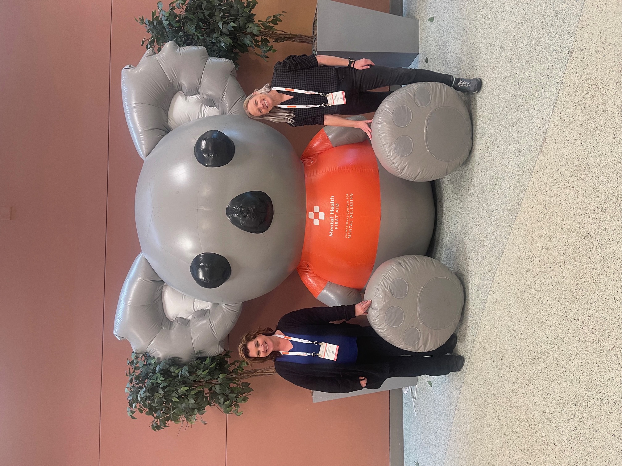 Two adults standing in front of a large blow up bear