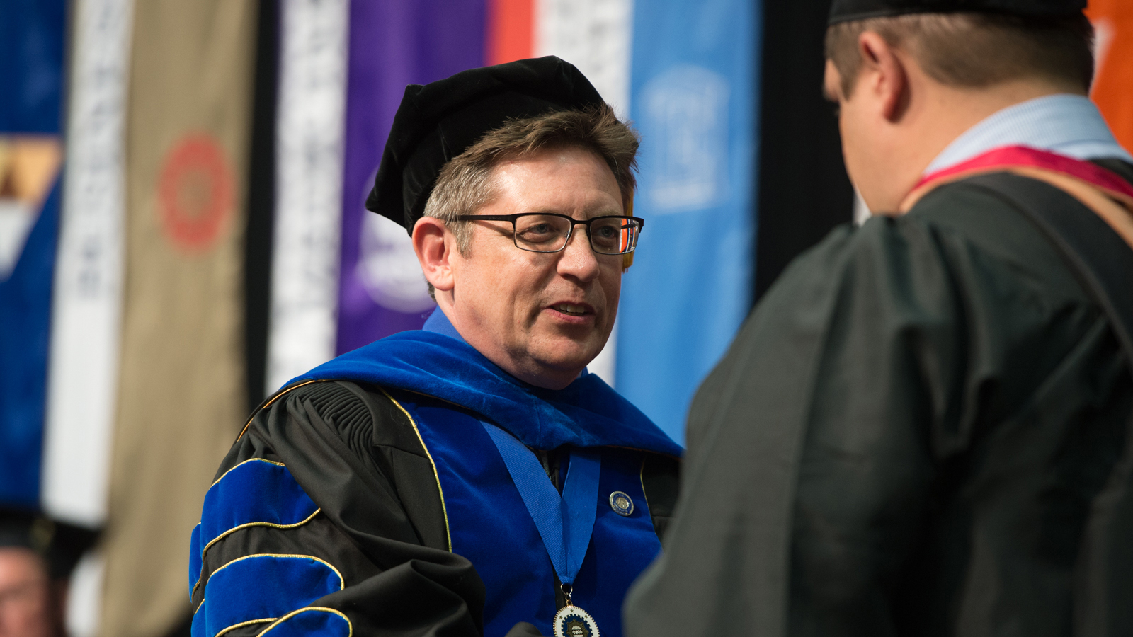 Dean Weinberg shaking graduate's hands from previous ceremony