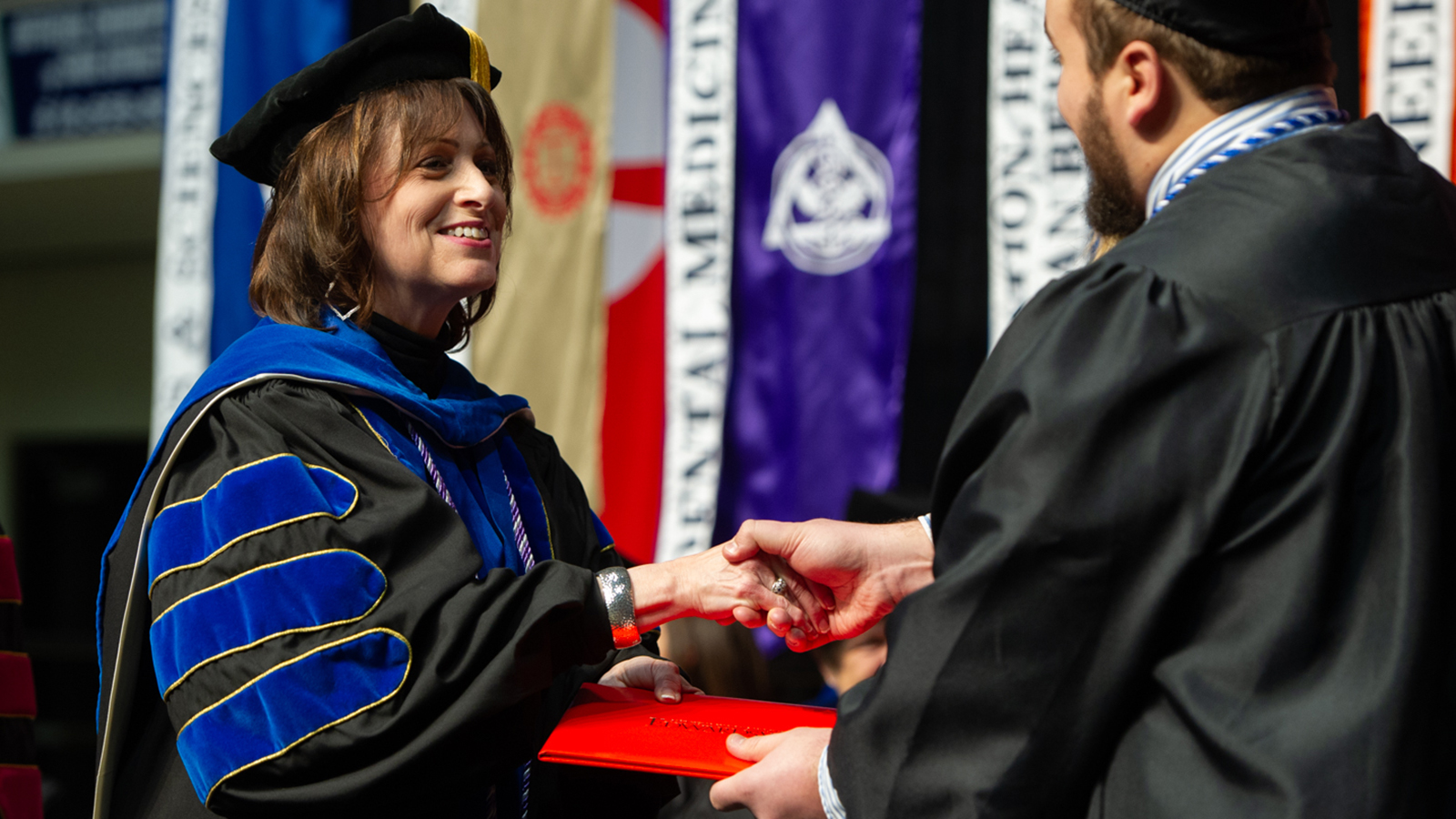 Dean Bernaix shaking graduate's hands from previous ceremony